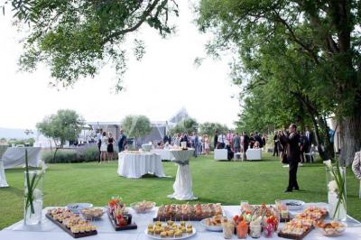 Vue aérienne d'un domaine rural avec bâtiments en pierre, arbres et vue sur une étendue d'eau calme en arrière-plan.