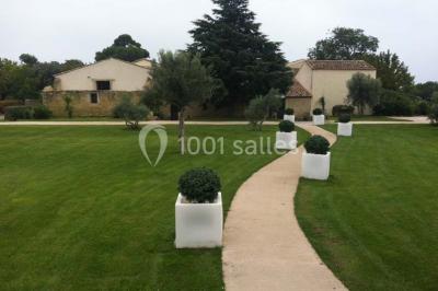 Vue aérienne d'un domaine rural avec bâtiments en pierre, arbres et vue sur une étendue d'eau calme en arrière-plan.