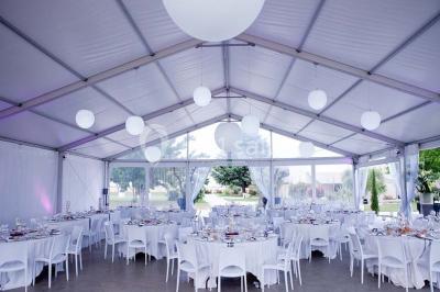 Vue aérienne d'un domaine rural avec bâtiments en pierre, arbres et vue sur une étendue d'eau calme en arrière-plan.