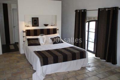 Vue aérienne d'un domaine rural avec bâtiments en pierre, arbres et vue sur une étendue d'eau calme en arrière-plan.