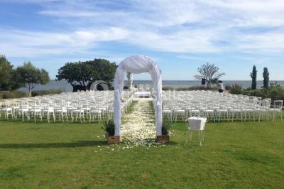 Vue aérienne d'un domaine rural avec bâtiments en pierre, arbres et vue sur une étendue d'eau calme en arrière-plan.