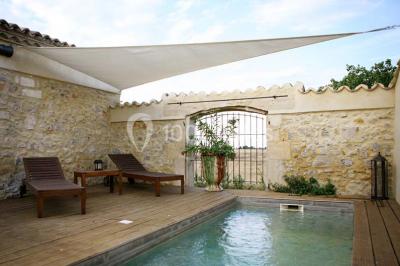 Vue aérienne d'un domaine rural avec bâtiments en pierre, arbres et vue sur une étendue d'eau calme en arrière-plan.