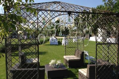 Vue aérienne d'un domaine rural avec bâtiments en pierre, arbres et vue sur une étendue d'eau calme en arrière-plan.
