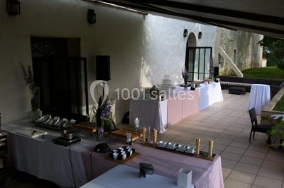 Vue aérienne d'un domaine rural avec bâtiments en pierre, arbres et vue sur une étendue d'eau calme en arrière-plan.
