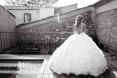 Vue aérienne d'un domaine rural avec bâtiments en pierre, arbres et vue sur une étendue d'eau calme en arrière-plan.