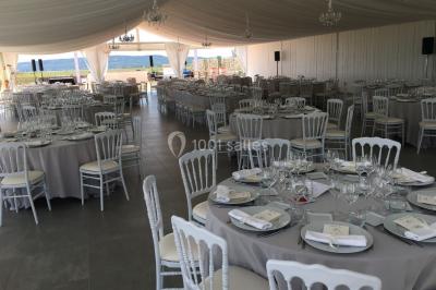 Vue aérienne d'un domaine rural avec bâtiments en pierre, arbres et vue sur une étendue d'eau calme en arrière-plan.