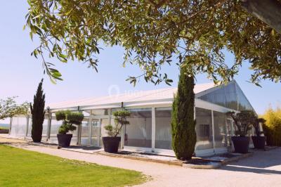 Vue aérienne d'un domaine rural avec bâtiments en pierre, arbres et vue sur une étendue d'eau calme en arrière-plan.