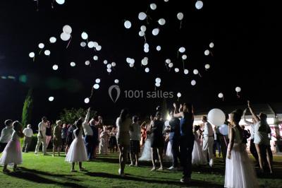 Vue aérienne d'un domaine rural avec bâtiments en pierre, arbres et vue sur une étendue d'eau calme en arrière-plan.