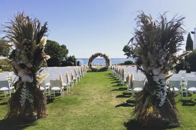 Vue aérienne d'un domaine rural avec bâtiments en pierre, arbres et vue sur une étendue d'eau calme en arrière-plan.