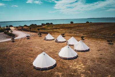 Vue aérienne d'un domaine rural avec bâtiments en pierre, arbres et vue sur une étendue d'eau calme en arrière-plan.