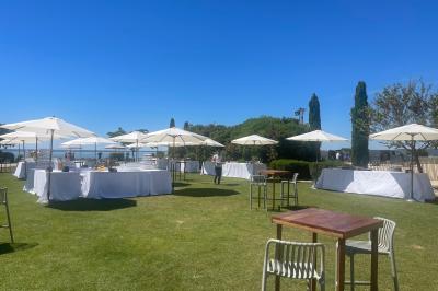 Vue aérienne d'un domaine rural avec bâtiments en pierre, arbres et vue sur une étendue d'eau calme en arrière-plan.