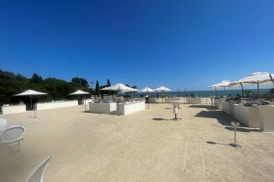 Vue aérienne d'un domaine rural avec bâtiments en pierre, arbres et vue sur une étendue d'eau calme en arrière-plan.