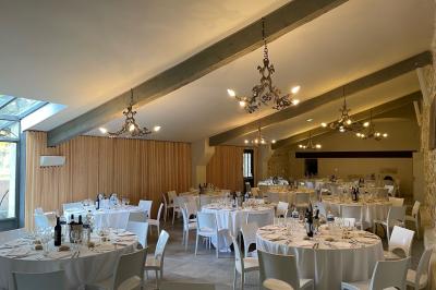 Vue aérienne d'un domaine rural avec bâtiments en pierre, arbres et vue sur une étendue d'eau calme en arrière-plan.