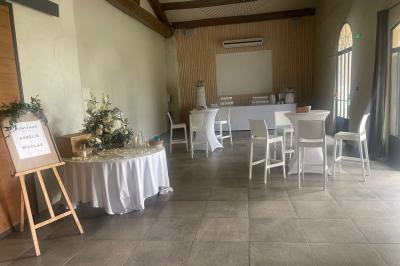 Vue aérienne d'un domaine rural avec bâtiments en pierre, arbres et vue sur une étendue d'eau calme en arrière-plan.