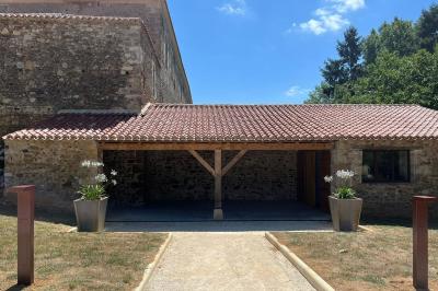 Salle en pierre avec tables hautes noires, boissons, plantes décoratives et chaises disposées pour un événement.