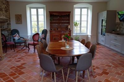 Salle en pierre avec tables hautes noires, boissons, plantes décoratives et chaises disposées pour un événement.
