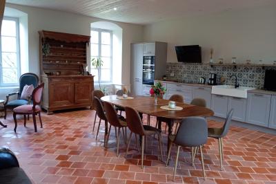 Salle en pierre avec tables hautes noires, boissons, plantes décoratives et chaises disposées pour un événement.