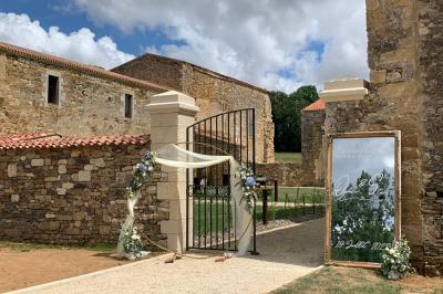Salle en pierre avec tables hautes noires, boissons, plantes décoratives et chaises disposées pour un événement.
