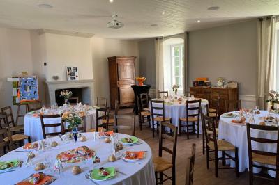 Salle en pierre avec tables hautes noires, boissons, plantes décoratives et chaises disposées pour un événement.