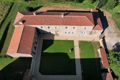 Salle en pierre avec tables hautes noires, boissons, plantes décoratives et chaises disposées pour un événement.