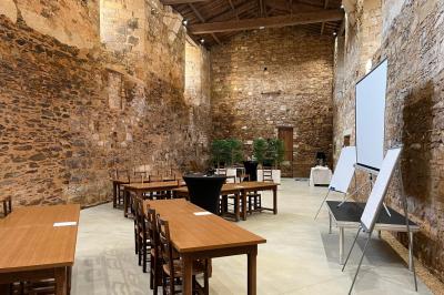 Salle en pierre avec tables hautes noires, boissons, plantes décoratives et chaises disposées pour un événement.