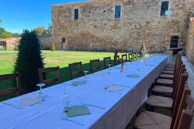 Salle en pierre avec tables hautes noires, boissons, plantes décoratives et chaises disposées pour un événement.