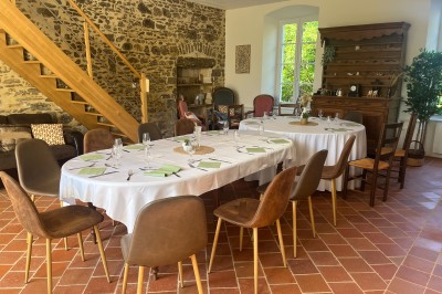 Salle en pierre avec tables hautes noires, boissons, plantes décoratives et chaises disposées pour un événement.