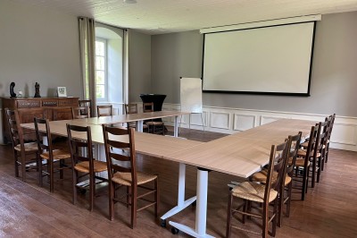 Salle en pierre avec tables hautes noires, boissons, plantes décoratives et chaises disposées pour un événement.