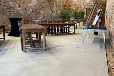 Salle en pierre avec tables hautes noires, boissons, plantes décoratives et chaises disposées pour un événement.