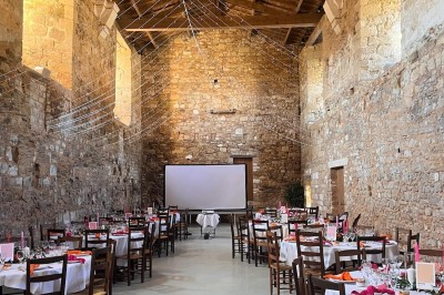Miniature Location salle Bournezeau (Vendée) - Abbaye de Trizay #56 Cour intérieure d'un bâtiment historique en pierre, aménagée avec des tables hautes et éclairée par un soleil éclatant.