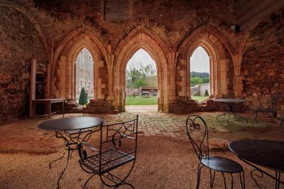 Table dressée avec nappes blanches, verres et seaux à glace, dans une salle en pierre avec de grandes fenêtres.