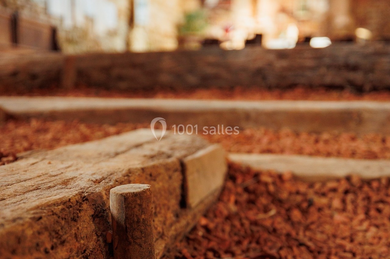 Vue rapprochée d'un sol en terre battue et briques rouges dans un bâtiment ancien avec des murs en pierre.
