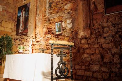 Table dressée avec nappes blanches, verres et seaux à glace, dans une salle en pierre avec de grandes fenêtres.