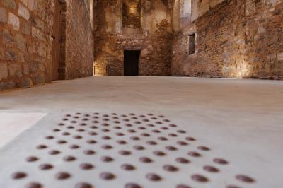 Table dressée avec nappes blanches, verres et seaux à glace, dans une salle en pierre avec de grandes fenêtres.