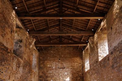 Table dressée avec nappes blanches, verres et seaux à glace, dans une salle en pierre avec de grandes fenêtres.