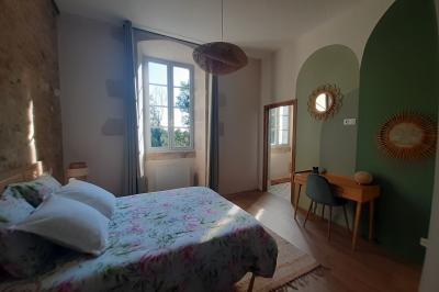 Table dressée avec nappes blanches, verres et seaux à glace, dans une salle en pierre avec de grandes fenêtres.