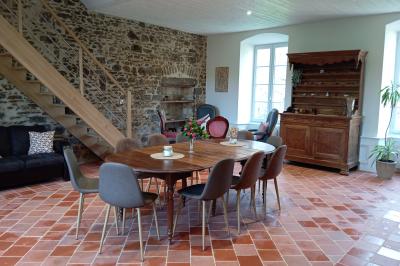 Table dressée avec nappes blanches, verres et seaux à glace, dans une salle en pierre avec de grandes fenêtres.