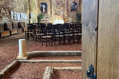 Table dressée avec nappes blanches, verres et seaux à glace, dans une salle en pierre avec de grandes fenêtres.