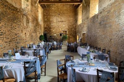 Table dressée avec nappes blanches, verres et seaux à glace, dans une salle en pierre avec de grandes fenêtres.