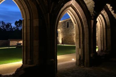 Table dressée avec nappes blanches, verres et seaux à glace, dans une salle en pierre avec de grandes fenêtres.