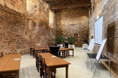 Table dressée avec nappes blanches, verres et seaux à glace, dans une salle en pierre avec de grandes fenêtres.