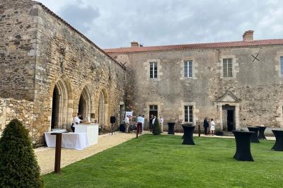 Table dressée avec nappes blanches, verres et seaux à glace, dans une salle en pierre avec de grandes fenêtres.