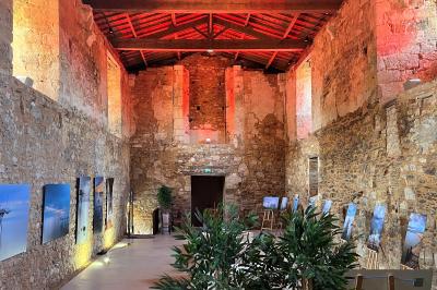 Table dressée avec nappes blanches, verres et seaux à glace, dans une salle en pierre avec de grandes fenêtres.
