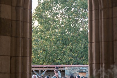 Table dressée avec nappes blanches, verres et seaux à glace, dans une salle en pierre avec de grandes fenêtres.