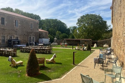 Table dressée avec nappes blanches, verres et seaux à glace, dans une salle en pierre avec de grandes fenêtres.
