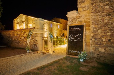 Table dressée avec nappes blanches, verres et seaux à glace, dans une salle en pierre avec de grandes fenêtres.
