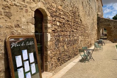 Table dressée avec nappes blanches, verres et seaux à glace, dans une salle en pierre avec de grandes fenêtres.