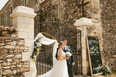 Table dressée avec nappes blanches, verres et seaux à glace, dans une salle en pierre avec de grandes fenêtres.