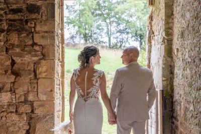 Table dressée avec nappes blanches, verres et seaux à glace, dans une salle en pierre avec de grandes fenêtres.