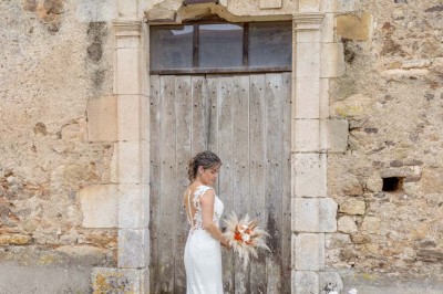Table dressée avec nappes blanches, verres et seaux à glace, dans une salle en pierre avec de grandes fenêtres.